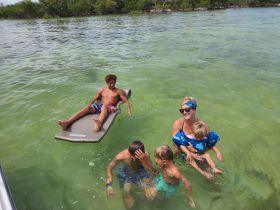 A joyful family enjoys a fun day in the water, with kids playing and relaxing on a floating mat — perfect for summer adventures and family bonding.