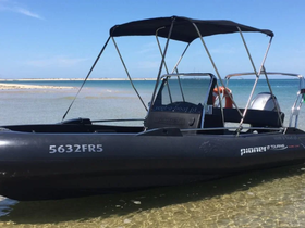 A sleek speedboat anchored in shallow waters, showcasing its modern design against a picturesque coastal backdrop.