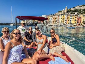 A cheerful group enjoys a sunny day on a boat, surrounded by colorful coastal buildings — perfect for memorable outings and celebrations on the water.