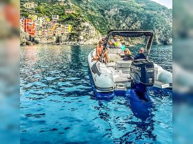 A lively group enjoys a day on the water aboard a boat, with colorful coastal buildings in the backdrop — perfect for exploring scenic destinations.
