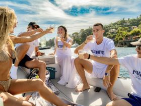A lively group enjoys cocktails aboard a boat, celebrating together against a picturesque backdrop — perfect for summer outings and memorable gatherings.