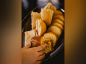 A hand reaches for a selection of freshly baked bread rolls, perfect for onboard snacks or meals during a boating trip.