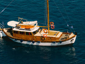 Aerial view of a beautifully crafted yacht cruising through clear blue waters, showcasing its elegant design and spacious deck.