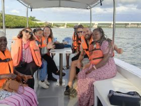 A cheerful group of friends enjoys a boat ride, all wearing life jackets and sharing smiles — a perfect moment for adventure on the water.