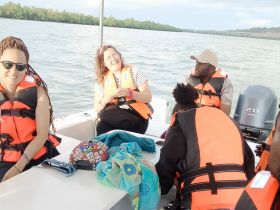 A cheerful group of friends enjoys their time on a boat, all wearing life jackets and sharing smiles, making for a perfect day on the water.