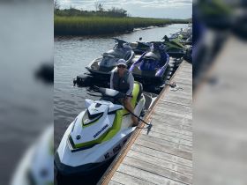 A woman enjoys a sunny day on a jet ski at the dock, surrounded by other watercraft — perfect for thrilling water adventures.