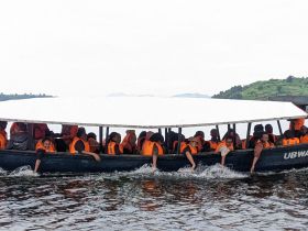 A lively group of individuals wearing life jackets enjoys a boat ride, showcasing the excitement of on-water activities and group adventures.