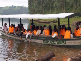 A lively group of children wearing safety vests enjoys a boat ride on a serene lake, creating memorable moments in nature.