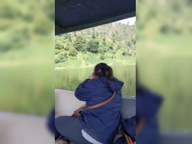 A guest enjoys the serene view of lush greenery while seated on a boat, capturing the beautiful landscape — a perfect moment for nature lovers.