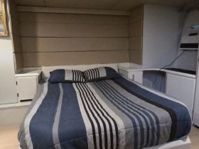Cozy cabin interior featuring a comfortable bed with striped bedding, perfect for relaxing on a boat getaway.