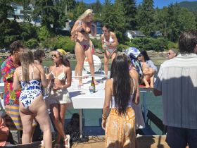 A vibrant group enjoys a lively party on a boat, complete with drinks and dancing under the sun — the perfect setting for summer celebrations.