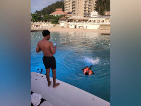 A group of young swimmers enjoys a fun day at the beach, with one wearing a life jacket while another captures the moment on a phone. Perfect for showcasing beach activities and family fun.