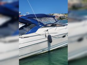 A sleek yacht docked in clear waters, showcasing its elegant design and blue canopy — perfect for luxury outings on the water.