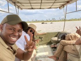 A cheerful group enjoys a boat safari, capturing a moment with elephants in the background — a perfect blend of adventure and wildlife observation.