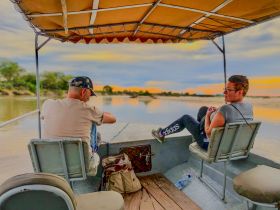 A couple enjoys a serene moment on a boat during sunset, perfect for romantic getaways or peaceful river cruises.