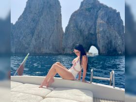 A woman relaxes on the deck of a yacht with stunning rock formations in the background, capturing the essence of a luxurious day on the water.