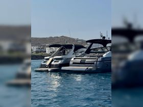 Two luxurious yachts docked in clear blue waters, showcasing their sleek designs against a picturesque coastal backdrop.