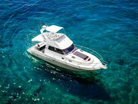 A stunning aerial view of a sleek yacht cruising through crystal-clear waters, perfect for luxury charters and ocean adventures.