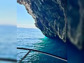 A stunning view of a rocky cave opening over turquoise waters, showcasing the natural beauty of the coastline — perfect for adventure seekers exploring hidden gems by boat.