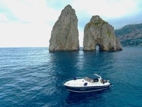 A scenic view of a boat navigating near iconic rock formations, showcasing the stunning coastline and crystal-clear waters — perfect for exploring the beauty of the area.