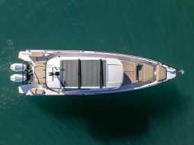 Aerial view of a sleek center console boat docked in clear waters, showcasing its spacious deck and modern design — perfect for day trips and water adventures.