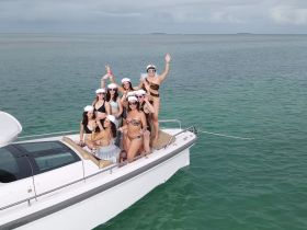 A lively group of friends celebrates aboard a boat, showcasing fun and camaraderie in a beautiful aquatic setting — perfect for bachelorette parties or group outings.
