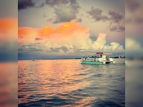 A picturesque sunset view of a pontoon boat cruising on calm waters, creating a serene atmosphere perfect for evening outings.