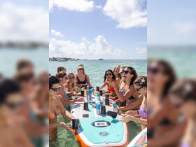 A lively group of friends enjoys a fun-filled day on the water, celebrating with drinks on a paddleboard — perfect for summer parties and beach outings.