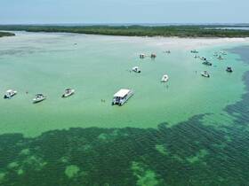 A vibrant scene at a sandbar with multiple boats anchored and guests enjoying the water — perfect for a fun day out on the water.