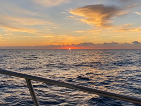 A stunning sunset over the ocean, viewed from the deck of a boat — perfect for capturing the serene beauty of evening cruises.