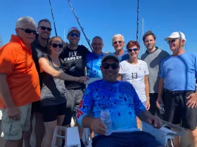 A cheerful group of friends poses together on a fishing boat, capturing the joy of their shared adventure at sea.
