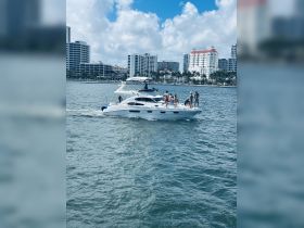 A lively group enjoys a day on a yacht, cruising through the water with the city skyline in the background — perfect for summer parties and celebrations.