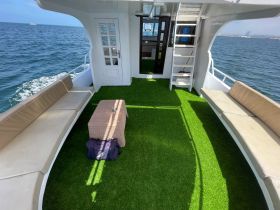 Interior view of a spacious boat lounge area featuring comfortable seating and a stylish table, perfect for relaxing while enjoying the open water.
