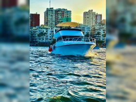 A stunning yacht navigates through the water, showcasing its sleek design against a backdrop of urban buildings — perfect for city cruises.