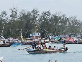 A lively group enjoys a day on the water aboard a traditional boat, surrounded by other vessels and vibrant flags, capturing the essence of local maritime culture.