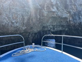A stunning view from the bow of a boat, showcasing a rocky cave entrance surrounded by clear waters — perfect for exploring coastal landscapes.