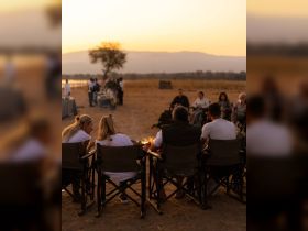 A group enjoys a cozy sunset gathering around a campfire, perfect for celebrating special moments in nature.