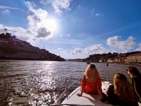 A group of friends enjoys a scenic river cruise under the bright sun, capturing the beauty of the waterfront and vibrant cityscape.