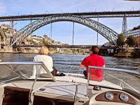 A couple enjoys a scenic boat ride under a stunning bridge, capturing the essence of river exploration and picturesque views.