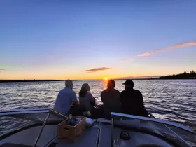 A group of friends enjoys a stunning sunset from the deck of a boat, creating a perfect backdrop for memorable moments on the water.