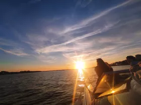 A group enjoys a stunning sunset view from their boat, creating a perfect backdrop for memorable moments on the water.