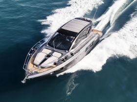 A stunning aerial view of a sleek yacht cruising through clear waters, showcasing its elegant design and performance on the open sea.