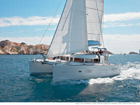 A stunning catamaran sails through clear blue waters, showcasing its sleek design against a backdrop of rocky cliffs — perfect for sailing enthusiasts and charter adventures.