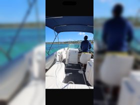 A view of the interior helm area of a boat, showcasing comfortable seating and the captain at the wheel, perfect for navigating through beautiful waters.