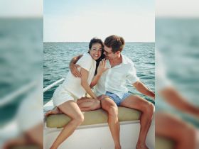 A joyful couple shares a moment on a boat, showcasing love and celebration against a beautiful water backdrop — perfect for romantic getaways.