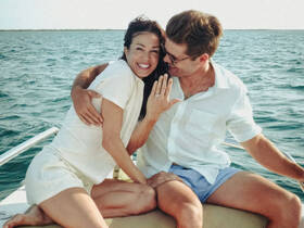 A joyful couple celebrates their engagement aboard a boat, showcasing love and happiness against a beautiful water backdrop.