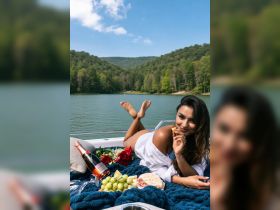 A woman enjoys a delightful picnic on a boat, surrounded by scenic views and a spread of grapes, cheese, and champagne — perfect for romantic getaways or special celebrations.