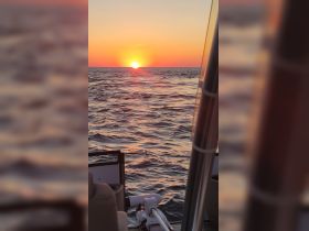 A stunning sunset view over the ocean from the deck of a boat, capturing the serene beauty of a perfect evening on the water.