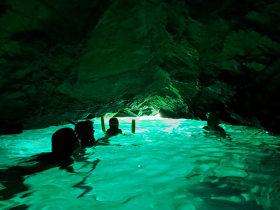 A group enjoys snorkeling in a stunning cave with glowing turquoise waters, creating an unforgettable underwater adventure.