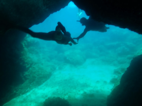 Two snorkelers explore an underwater cave, showcasing the beauty of marine life and adventure in the ocean.